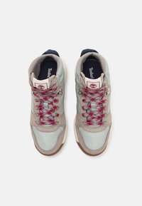 Pair of Timberland sneakers with gray and beige panels, red and gray patterned laces, and dark blue insoles, viewed from above on white background.