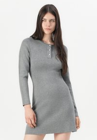 Robe grise à manches longues en tissu tricot doux, avec un col henley à trois boutons et une silhouette ajustée.