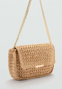 Tkana torba od slame u prirodnoj bež boji, s zlatnim lanac remenom i pravokutnim poklopcem s metalnim naglaskom sprijeda.