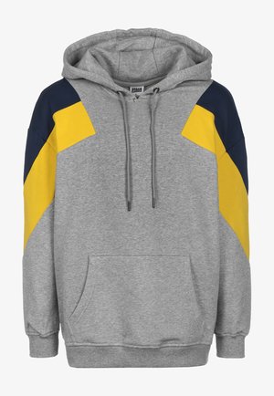 Grijze hoodie met een voorzak, voorzien van marineblauwe en gele diagonale accenten op de mouwen. Inclusief een capuchon met trekkoord.
