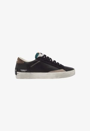 Sneaker in pelle nera con suola grigia texturizzata e dettagli marroni. Presenta una chiusura a zip e una linguetta in tessuto blu. Il testo sul lato recita "DISTRESSED WITH NO STRESS."