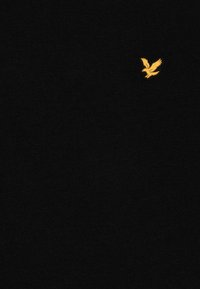 Black t-shirt made of soft fabric featuring a small yellow embroidered eagle logo on the left chest area. Simple and classic design.