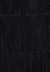 Svart fransad mockastoff med vertikala ränder, som har en mjuk textur och ett enhetligt mönster som täcker hela ytan.