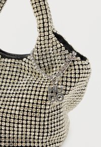 Μαύρη γυναικεία τσάντα διακοσμημένη με ασημένιες καρφίτσες, με ασημένια αλυσίδα και κυκλικό γούρι με την επιγραφή «HUGO». Λείο υλικό και στιβαρός σχεδιασμός.