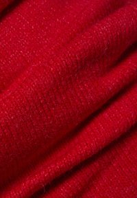 Red soft wool fabric with fine knit texture and visible fibers, shown in gentle folds.