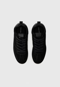Sneakers neri con tomaia in suede, dotati di una punta liscia, lacci neri e una linguetta sul tallone. Design semplice e lineare.