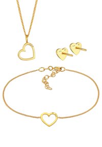 Smykkesæt i guldplateret, der inkluderer et hjerteformet vedhæng på en kæde, matchende hjerteformede øreringe og et armbånd med hjerte-motiv.