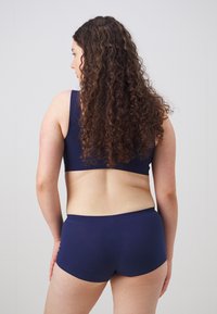 Navy blue seamless underwear set featuring a simple bralette and shorts, made from soft fabric with a smooth texture and no visible hardware.