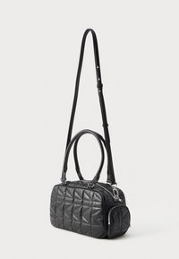 Černá prošívaná kabelka s dvojitými rukojeťmi a odnímatelným ramenním popruhem. Má stříbrný zip a geometrický vzor na povrchu.