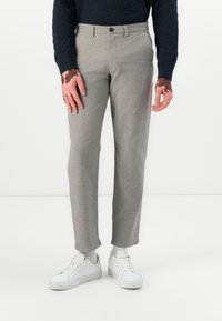 Gray tailored pants with a subtle herringbone pattern, featuring a button closure. Worn with white sneakers and a dark blue sweater.