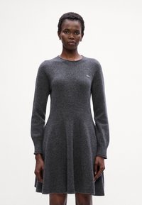 Abito grigio a maglia con maniche lunghe, scollatura rotonda, gonna svasata e sottile dettaglio del logo del marchio sul petto. Tessuto morbido, vestibilità casual.