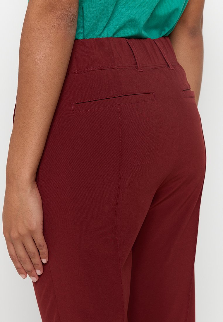 Pantalons bordeaux en tissu texturé, avec une taille plate et deux poches arrière, présentés de dos avec une finition lisse.