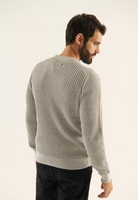 Suéter de punto acanalado gris con cuello redondo, que presenta mangas largas y una cintura ajustada, mostrado desde la parte posterior sobre un fondo neutro.