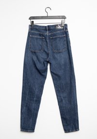 Mörkblå denimjeans med rak benprofil, med två bakfickor och en svart logotypplatta på midjan. Slät textur med lätt blekning.