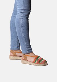 Sandali espadrille intrecciati multicolori con una tomaia a motivo, suola in juta naturale e accentuazioni in suede marrone. Cinghie alla caviglia regolabili.