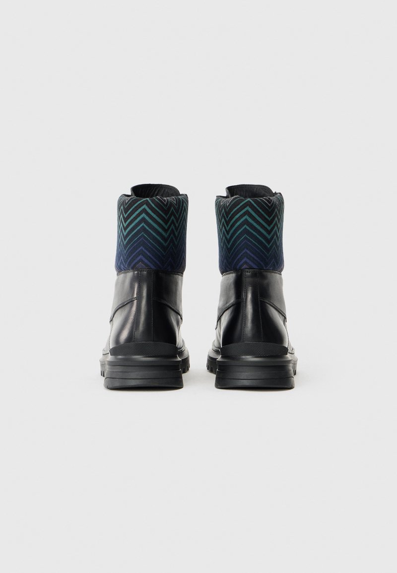 Sorte ankelstøvler med en tekstureret læderkrop, der har en mønstret krave i blå og grøn stof med chevron design. Gummisål, rund tå.