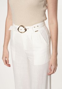 Witte linnen broek met een wijd beenontwerp, voorzien van een gestructureerde afwerking, een gouden ovale ceintuurgesp en zijplooien voor extra detail.