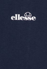 T-shirt in cotone blu navy con logo "ellesse" bianco e un accento a semicerchio sopra il testo. Texture liscia, design semplice.
