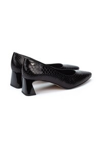 Zapatos de tacón de piel negra con un patrón texturizado de serpiente, punteras afiladas y un tacón grueso y brillante. Presenta un pequeño logo en la parte posterior.