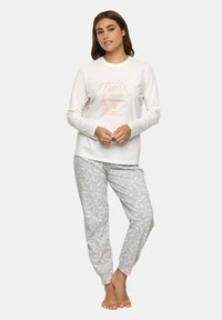 Maglietta da pigiama bianca a maniche lunghe con stampa "È tempo di caffè", abbinata a pantaloni grigi con motivo di tazze da caffè. Materiale in cotone, vestibilità comoda.