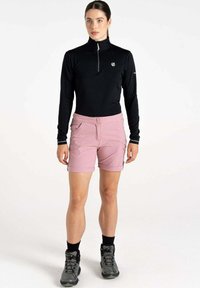 Schwarzes langärmliges Oberteil mit Viertel-Reißverschluss, pinkfarbene Cargo-Shorts mit Vorder- und Seitentaschen sowie graue Wanderschuhe mit schwarzen Socken.