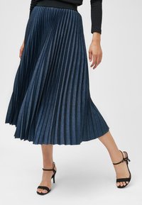 Plissédenimrok in diepblauw, met een brede elastische tailleband, vloeiende pasvorm en zachte textuur met een subtiele glans.