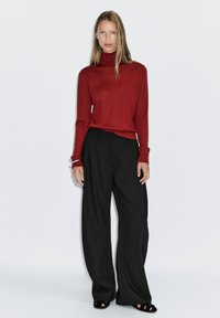 Rode coltrui gecombineerd met hoge taille zwarte wijdgepoot pantalons. Gladde textuur, minimalistisch ontwerp en geen zichtbare patronen of versieringen.
