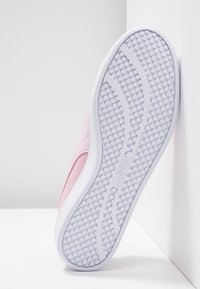 Rosa mockaskor med vit gummisula, med en strukturerad prickmönster, rund form och en slät yta.