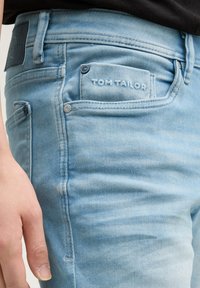 Helles blaues Denim-Jeans mit einem gestickten Logo auf der Gesäßtasche, schlankem Schnitt und silberfarbenen Hardware-Akzenten.