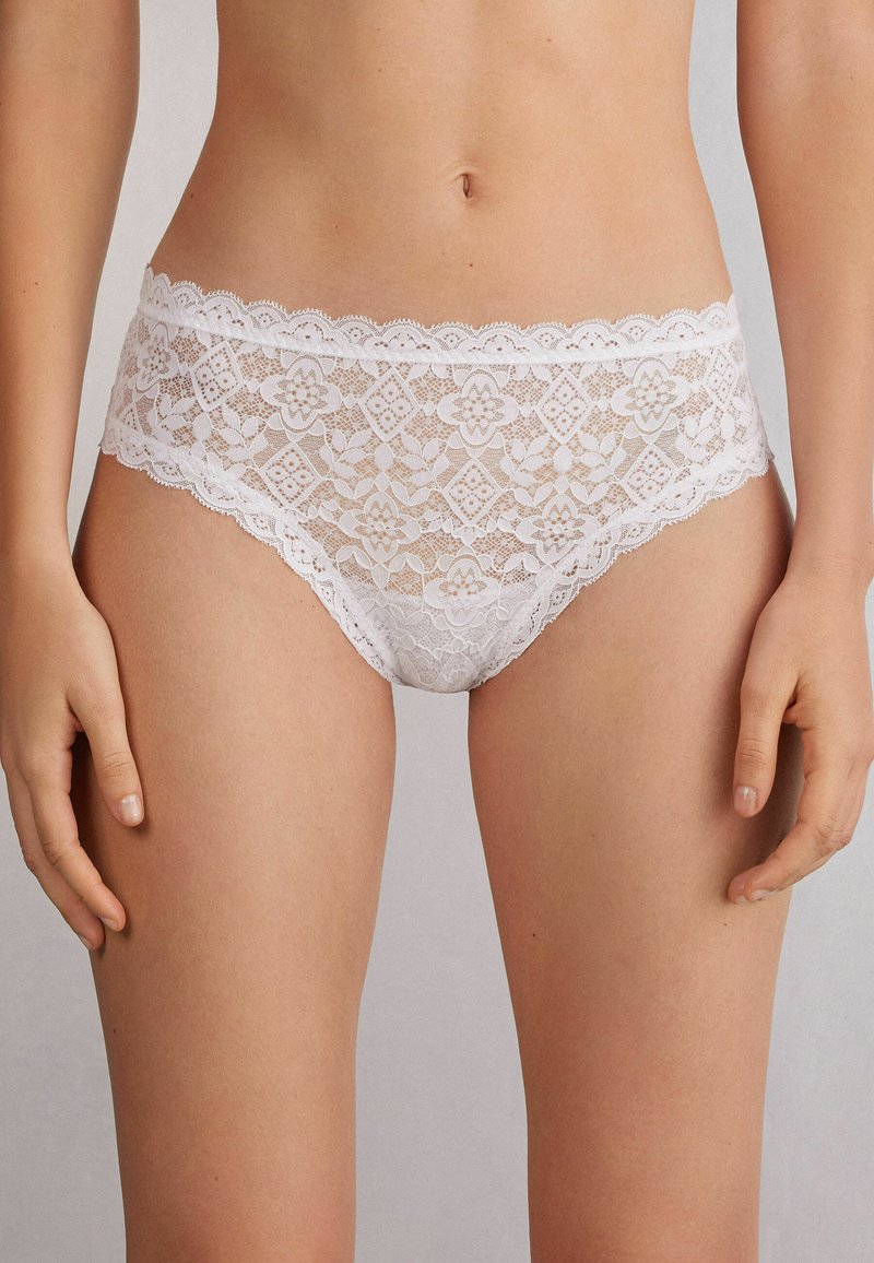 Witte kanten bikini-stijl ondergoed met bloempatronen en golvende randen, met een doorschijnende textuur en een gedetailleerd ontwerp.