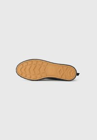 Semelle de chaussure en caoutchouc dotée d'un design texturé et détaillé en beige avec des bords noirs. Comprend un logo rond au centre et des motifs de traction.