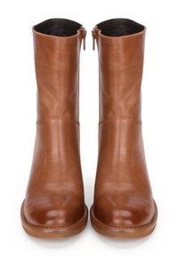 Botas de cuero marrón hasta el tobillo con un acabado suave, punta redondeada y cremalleras laterales, que presentan un forro interior oscuro en contraste y costuras mínimas.