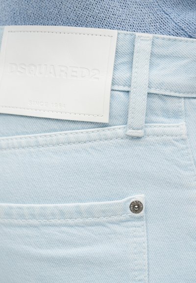 Φωτεινό μπλε τζιν από denim με μπροστινή τσέπη, θηλιά για ζώνη, μεταλλικό κόμβο και ένα λευκό κεντητό λογότυπο DSQUARED2 πάνω από την τσέπη.