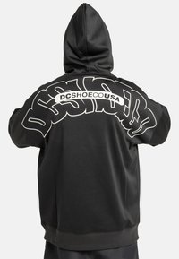 Zwarte hoodie met een grote witte graphic op de achterkant met de tekst "DCSHOECOUSA." Voorzien van een capuchon met trekkoord en geribde boorden.