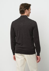 Suéter de punto gris oscuro con mangas largas, un cuello alto y puños acanalados. La tela parece suave y lisa al tacto.