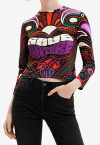 Krátký rukáv a dlouhý rukáv, crop top s barevným, psychedelickým potiskem, který obsahuje výrazný text. Vyrobeno z elastického materiálu, převážně v purpurové, zelené a červené barvě.