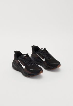Black athletic shoes with a breathable mesh upper, white Nike swoosh, textured sole, and contrasting brown accents. Includes reinforced heel.