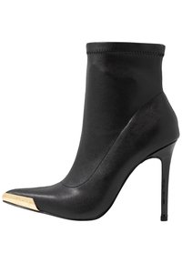 Czarne skórzane botki na wysokim obcasie do kostki z szpiczastym noskiem i złotym metalowym detalem na czubku.