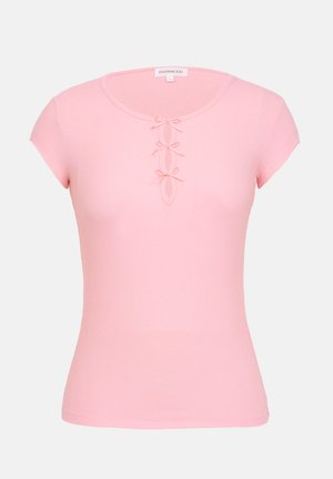 Maglietta rosa a maniche corte con coste, caratterizzata da un collo rotondo e fiocchetti decorativi lungo la patta, realizzata in un tessuto morbido ed elasticizzato.