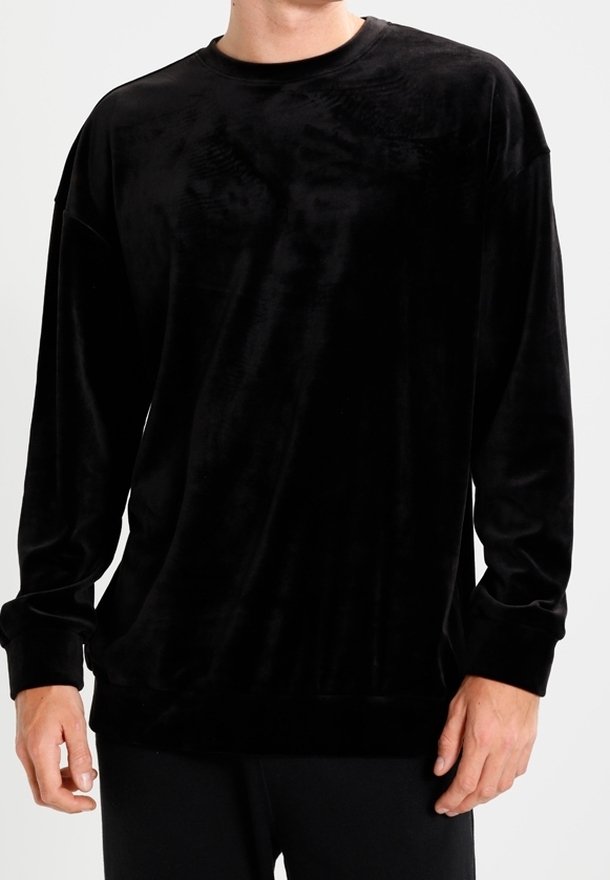 Sweat-shirt noir en velours à manches longues avec un col rond, une coupe décontractée et des poignets côtelés, présentant une texture lisse et brillante.