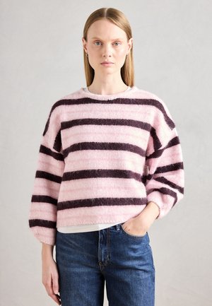 Pull rayé rose et marron foncé en matière pelucheuse, avec un col rond et une coupe décontractée, associé à un jean bleu.
