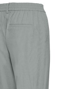 Pantalon gris clair à taille élastique, présentant une texture lisse avec une seule poche arrière, conçu pour une coupe décontractée.