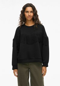 Felpa nera con un design a frange sul petto. Maniche lunghe e scollatura a girocollo con vestibilità rilassata. Tessuto morbido.