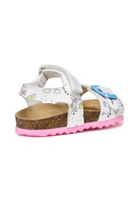 Sandalias blancas con un patrón de unicornios y nubes, hebilla azul, plantilla de corcho y suela rosa dentada. Cuenta con correas ajustables para un mejor ajuste.