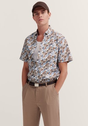 Kurzärmliges Hemd mit Knopfleiste, das ein blaues, braunes und cremefarbenes Blumendesign aufweist. Kombiniert mit beigen Hosen und einem braunen Gürtel.