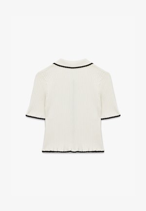 Ribbed valkoinen lyhythihainen paita, jossa on musta reunus kauluksessa ja hihoissa. Helma on hienovaraisesti levenevä. Pehmeä, kevyt kangas.