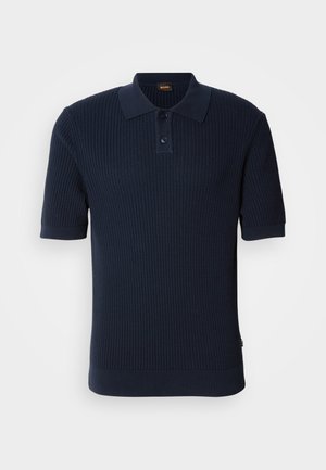 Marineblå ribbet polo-skjorte med to knapper, korte ermer og flat krage. Stoffet har en teksturert overflate og en figursydd silhuett.