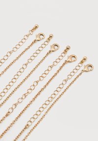 Πέντε επεκτάσεις από χρυσή αλυσίδα με κούμπωμα σε σχήμα αστακού, τοποθετημένες παράλληλα σε λευκό φόντο, που δείχνουν διαφορετικά μεγέθη κρίκων και άκρα κλειδώματος.