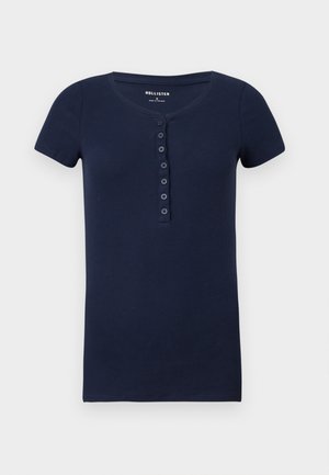 Navy blue short-sleeved ribbed t-shirt with a rounded neckline and a button placket featuring six matching buttons. Soft cotton material.