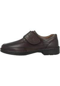 Brown leather shoe with a rounded toe, a stitched design, and a Velcro strap across the upper. Features a textured rubber sole.